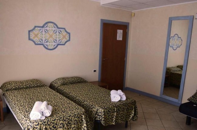 Camera con due letti singoli e asciugamani arrotolati.