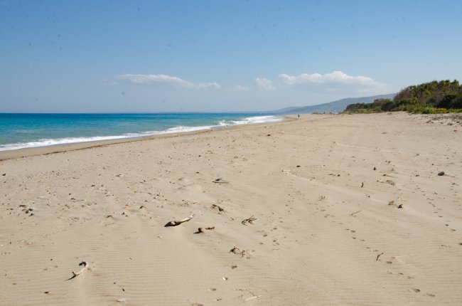 Spiaggia deserta con cielo sereno e mare azzurro.