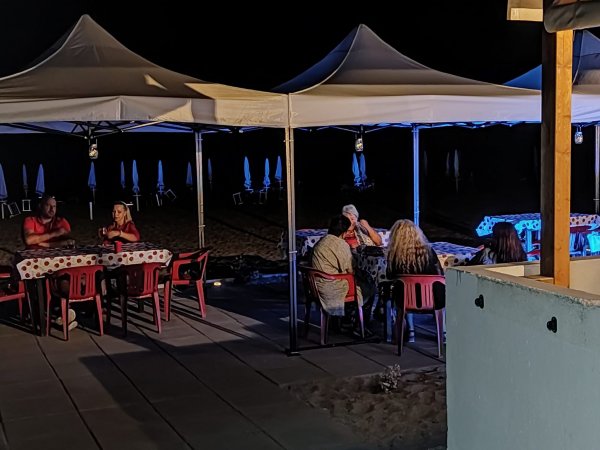 Persone sedute sotto gazebo in spiaggia di notte.