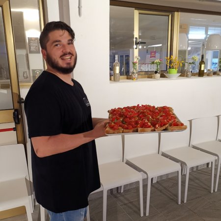 Uomo con vassoio di bruschette in una sala interna.