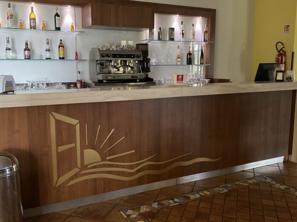 Bar con bancone in legno e mensole con bottiglie.
