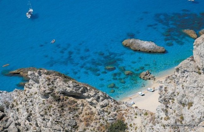 Spiaggia di sabbia con mare turchese e rocce.