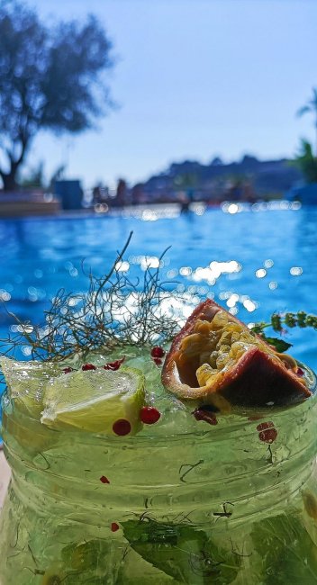 Un cocktail tropicale vicino a una piscina illuminata dal sole.