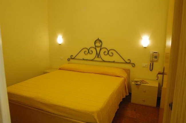 Camera da letto con letto matrimoniale e pareti gialle, illuminata da due applique.