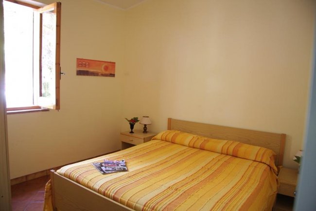 Camera semplice con letto matrimoniale e finestra.