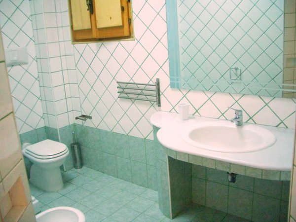 Un bagno con piastrelle verdi, un lavandino ampio e un WC.