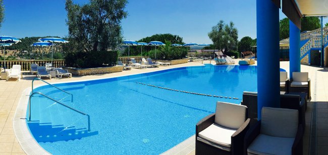 Piscina con colonne blu e sedie bianche.