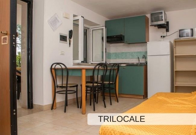 Cucina con tavolo e sedie, accanto a un letto.