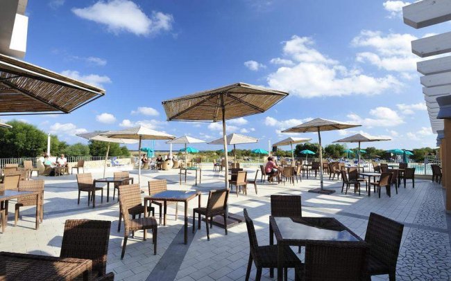 Terrazza esterna con tavolini e ombrelloni, cielo sereno.